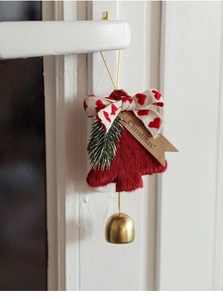 Detail of red plush Christmas tree ornament with bell and Merry Christmas tag