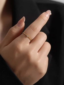Close-up of a minimalist gold twisted rope ring with a small zircon on a model's index finger