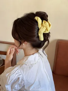 Detailed back view of a yellow pleated fabric hair claw clip on a stylish hair bun