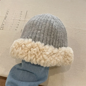 Detail of grey knitted bucket hat with thick cream faux fur brim on denim background