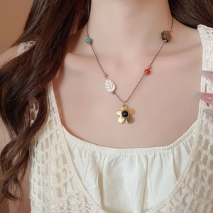 Gros plan sur un collier ethnique avec pendentif fleur dorée et perles en bois naturel