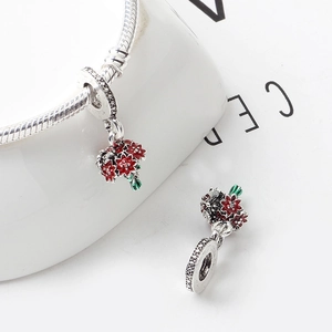 Silver flower pendant with red and green enamel on a bracelet against a white background