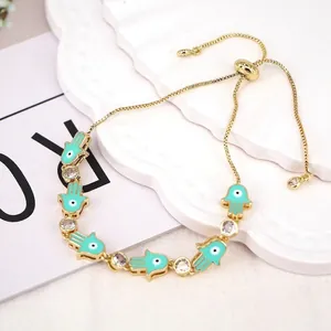 Close-up of golden adjustable Hamsa hand bracelet with turquoise enamel and evil eye charm