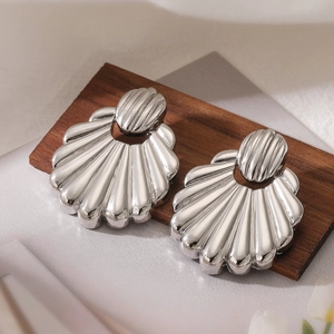 Minimalist silver shell heart earrings with a polished metallic finish on a wooden stand