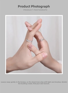 Close-up of vine-shaped open ring and hammered metal band on a couple's hands