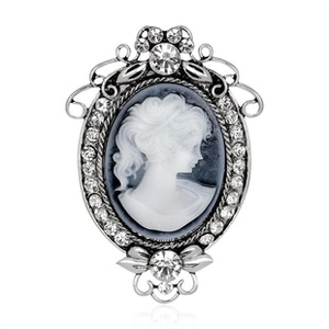 Detailed close-up of a silver vintage cameo brooch with white portrait and crystal trim