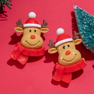 Macro de boucles d'oreilles rennes de Noël en résine avec bonnets rouges sur fond rouge