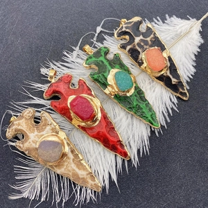 Arrow-shaped natural stone pendants with gold-plated trim on a decorative white feather