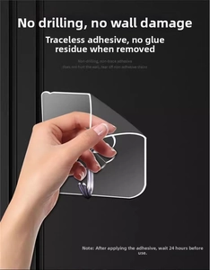 Detail showing hand applying a transparent adhesive wall hook on a smooth dark surface