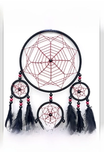 Détail d'un attrape-rêves artisanal avec cercles noirs, filet rouge et plumes sombres