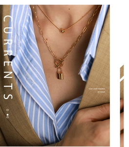 Detail shot of double-layered gold necklace with lock pendant and bead chain on a model