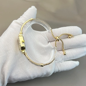Elegant gold square watch with crystal bezel and adjustable mesh bracelet on display