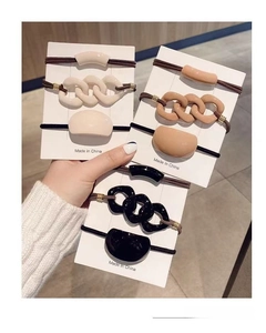 Detail view of a 9-piece beige and coffee colored hair scrunchie set in card packaging