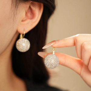 Close-up of colorful rhinestone sphere drop earrings worn by a model in soft lighting