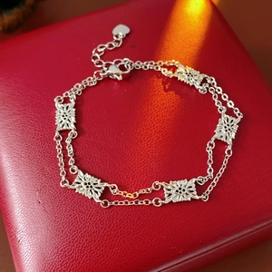 Detailed close-up of a silver floral bracelet with double chains on a red jewelry box