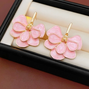Macro detail of pink flower earrings with gold edges on a beige velvet jewelry pad