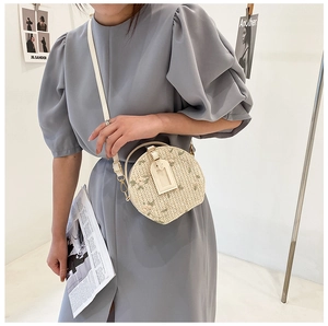 Detail of round straw crossbody bag with floral embroidery and hanging card holder accessory