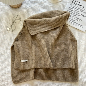 Detail of earthy tone ribbed knit shawl featuring three retro buttons and side opening