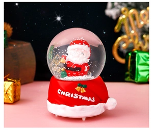 Close-up of Santa Claus snow globe with liquid glitter on a festive resin base