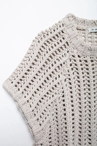 Détail de pull en maille épaisse crème montrant le motif découpé géométrique