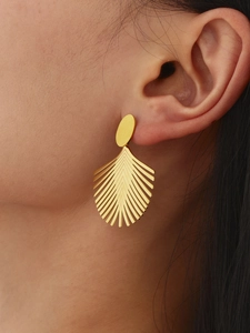 Detailansicht goldener Edelstahl Kokosblatt Ohrringe am Modell für einen Strand-Look