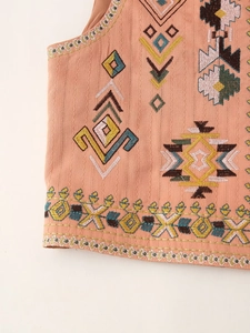 Close-up of colorful ethnic embroidery on pink vest showing detailed geometric patterns