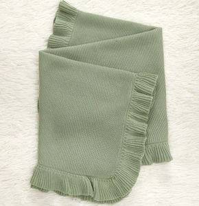 Detail of sage green ruffled edges on thick knitted cotton baby blanket for strollers