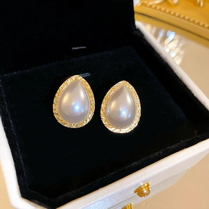 Detail of drop-shaped pearl earrings with gold wheat texture in a black jewelry box