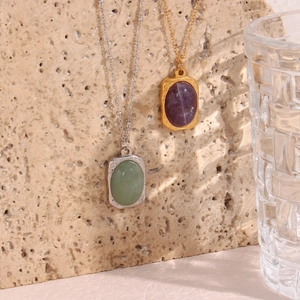 Detailed macro of gold and silver vintage oval gemstone necklaces on beige stone background