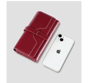 Detailed view of red leather wallet with white stitching next to a smartphone