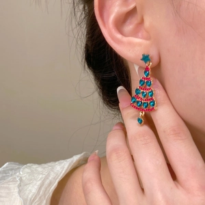 Close-up of elegant Christmas tree stud earrings with green heart-shaped crystals