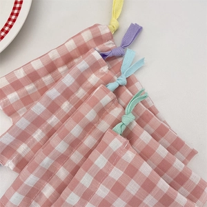 Close-up of pink checkered cotton drawstring bag with colorful cords for small gift storage
