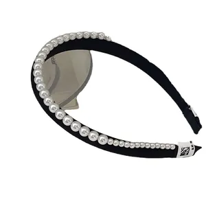 Elegant black satin headband with gradient white pearls displayed on a reflective mirror