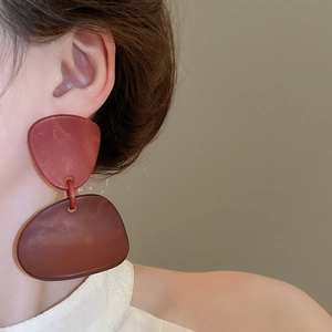 Close-up of deep red irregular geometric acrylic drop earrings on model's ear