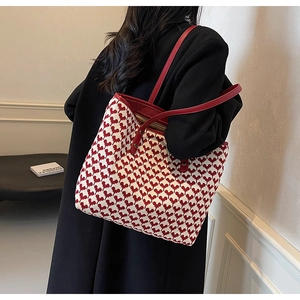 Detail of red heart patterns on a large tote bag shown on a female model's shoulder