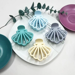 Detailed view of four shell-shaped matte hair claws in blue, green, grey, and beige colors