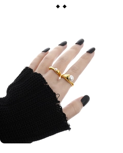 Detail view of gold-plated fluid wave rings with white pearls on a model hand