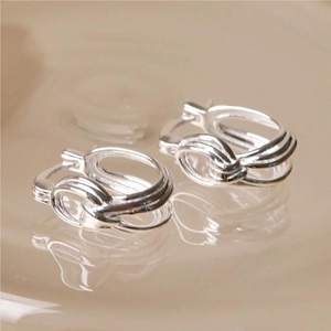 Macro shot of minimalist silver knotted stud earrings with a polished metallic finish