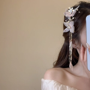 Détail d'une pince à cheveux fleur rose en organza avec perles et pendentif à pompon doré