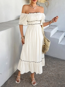 Detail of off-shoulder smocked bodice and black ruffle trim on white midi dress