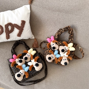 Leopard print plush handbag featuring cute dog pendants with colorful bows on a cozy sofa