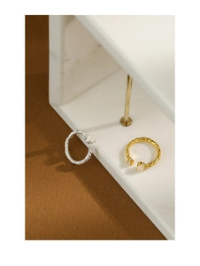 Macro detail of gold and silver textured rings with opal stones on marble blocks