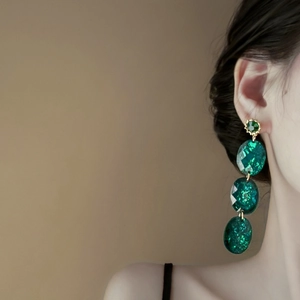 Vintage emerald geometric drop earrings with gold accents on an elegant model