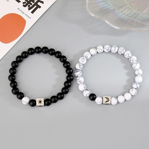 Detailed view of matte black and marble white beaded bracelets with sun and moon charms