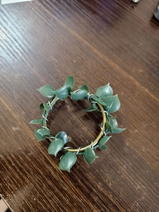 Detail of rustic farmhouse napkin ring with lush green faux leaves on golden metal loop
