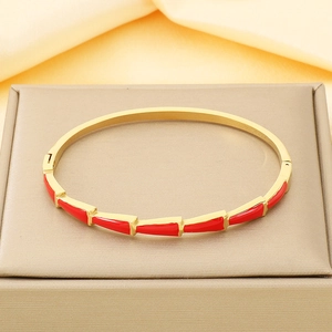 Detail of 18K gold plated bangle featuring red triangle enamel segments on a jewelry box