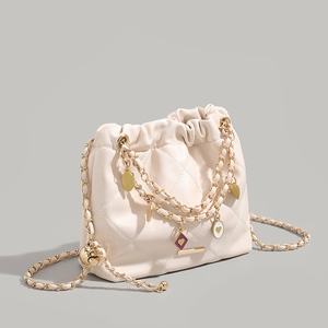 Cream quilted bucket bag with gold chain and heart charms in a 45-degree side view