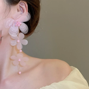 Detail of pink chiffon flower tassel earrings with golden chains on a female model