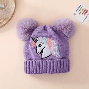 Detail of purple knitted hat for girls featuring unicorn embroidery and dual pom poms