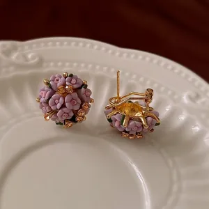 Elegant purple ceramic flower cluster earrings with rhinestones on a porcelain plate